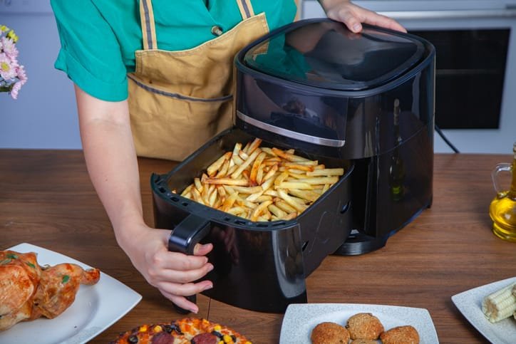 Cesta de una freidora de aire con patatas fritas doradas