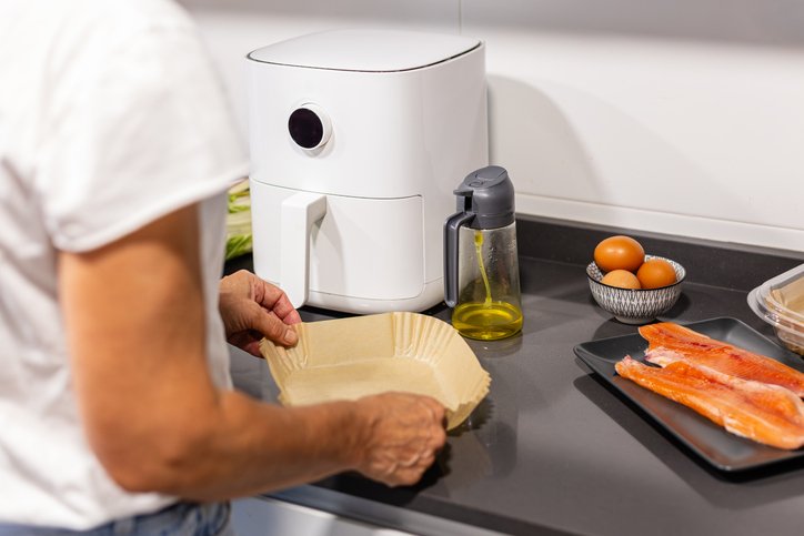 Colocando una bandeja de papel en la freidora de aire antes de cocinar el salmón